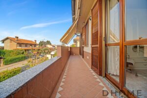 Balcone ampio con vista su quartiere residenziale, pavimentato in terracotta e con tapparelle in legno.