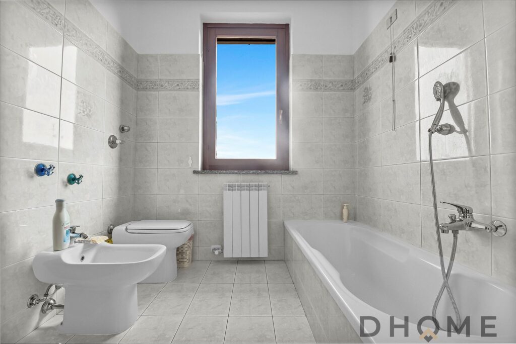 Servizi bagno moderno con vasca e finestra naturale, rifiniture di pregio e arredi eleganti.