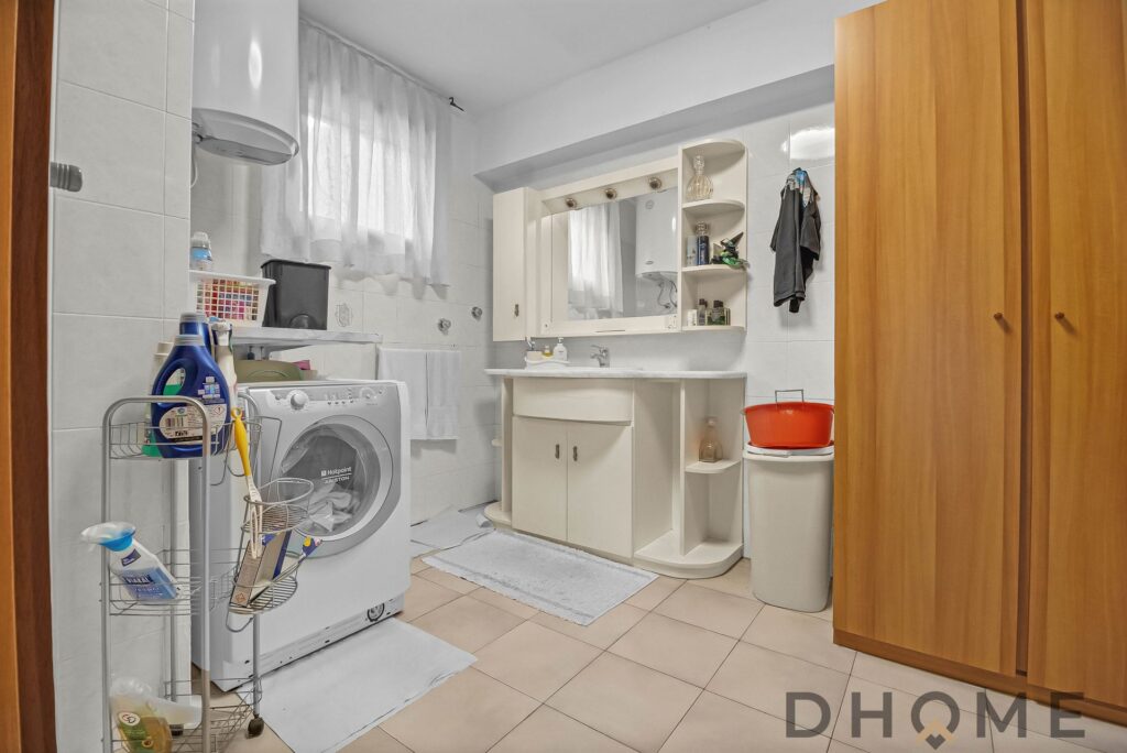 Lavanderia moderna con mobili bianchi e elettrodomestici essenziali, spazio pratico e funzionale.