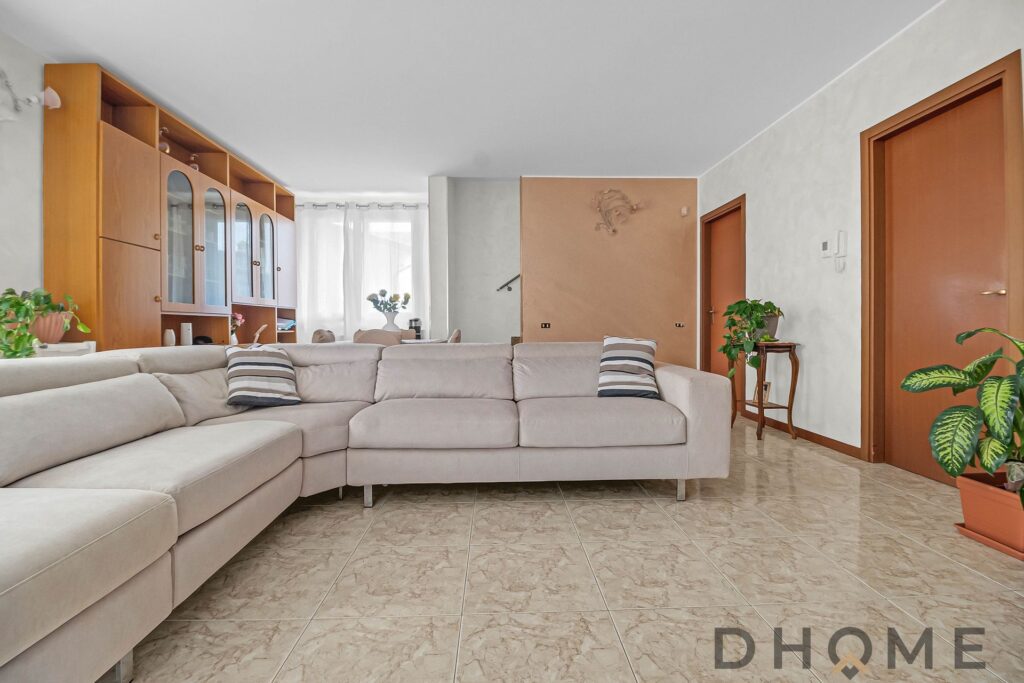 Divano beige angolare con cuscini decorativi in salotto, arredamento moderno e accogliente.