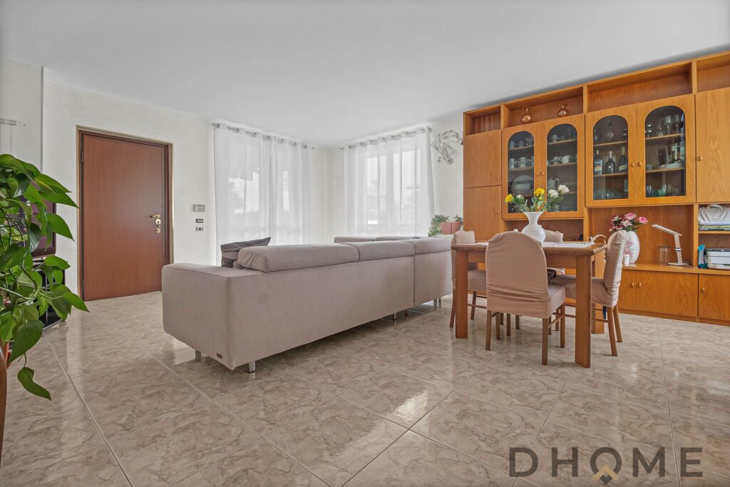 Elegante soggiorno con divano e tavolo in legno, luce naturale e arredi moderni.