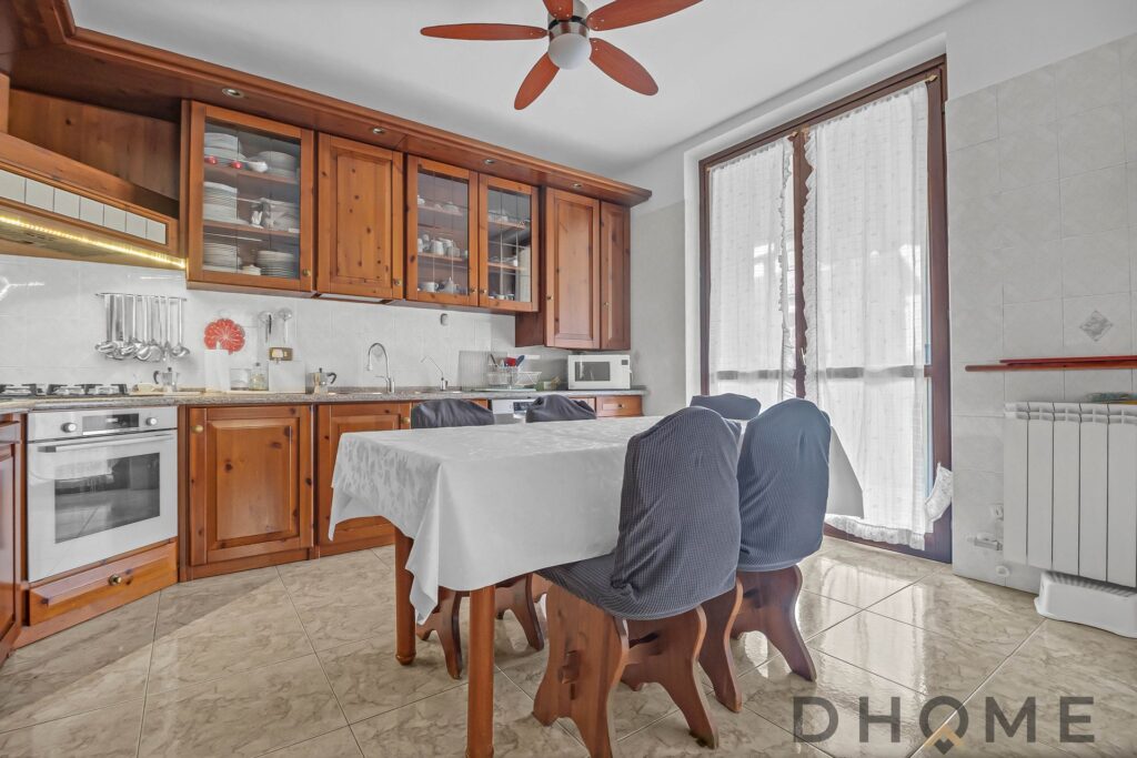 Polished wooden kitchen cabinets with dining table and chairs, bright sunlight through large windows, modern home interior decor.