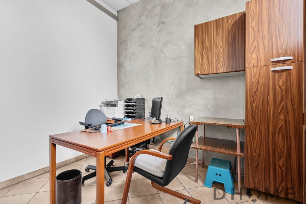 Scrivania da ufficio in legno con sedia e armadiature, ambiente di lavoro funzionale e ben organizzato.