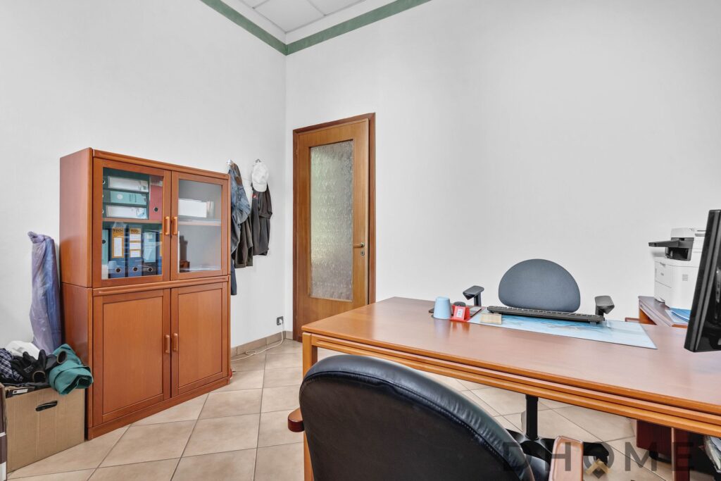 Scrivania ufficio moderna con sedia ergonomica e mobile in legno in ambiente professionale.