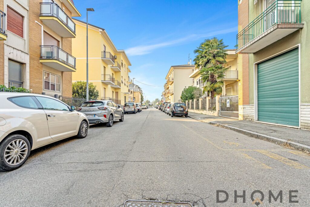Auto parcheggiate su strada residenziale con edifici moderni e palme, zona tranquilla e ben collegata.