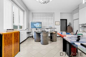 Sedie ufficio moderne in tessuto grigio e tavolo circolare in vetro, ambiente lavorativo luminoso.