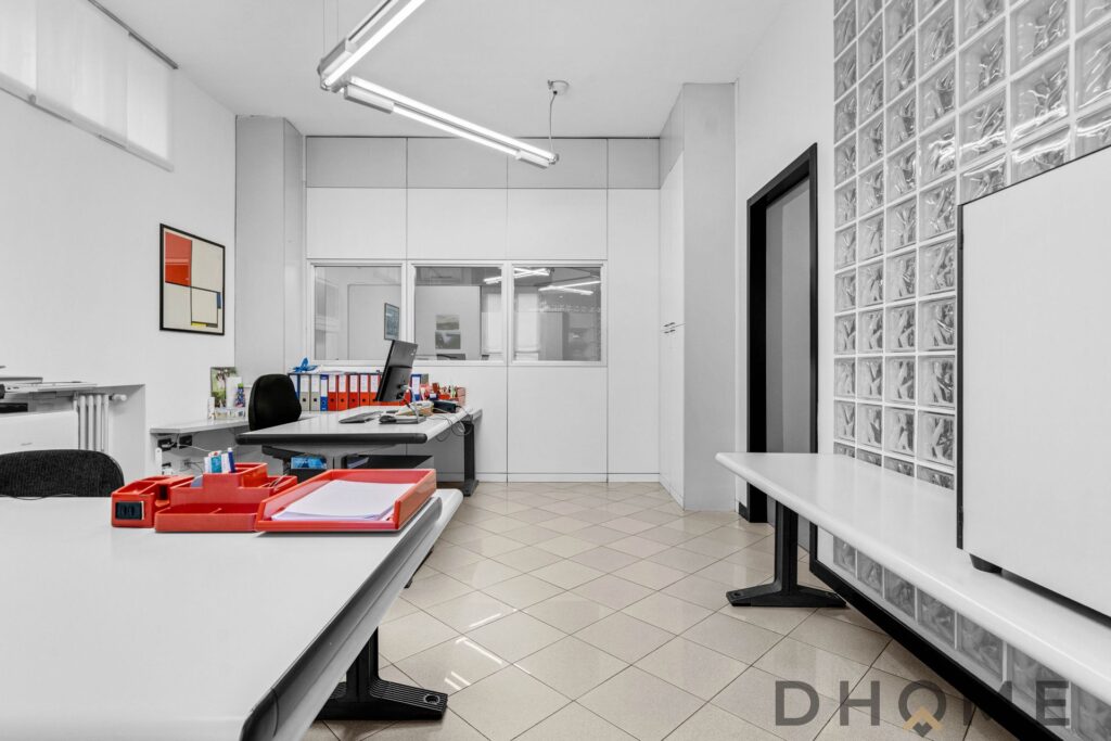 Spazio ufficio moderno e funzionale con scrivanie organizzate, arredamento minimalista e illuminazione a LED.