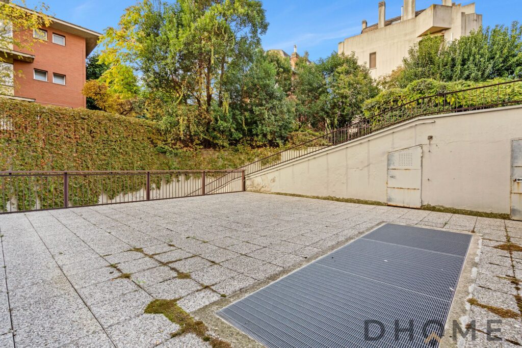 Spazio esterno in pietra con grate di accesso, terrazza con vista su natura e case, ambiente ideale per relax e convivialitĆ all'aperto.