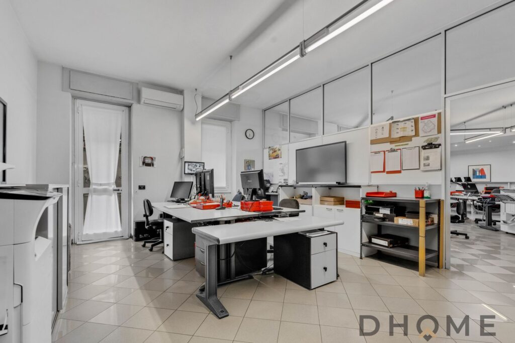 Ufficio moderno con postazioni di lavoro e pareti divisorie, ambiente professionale e funzionale.