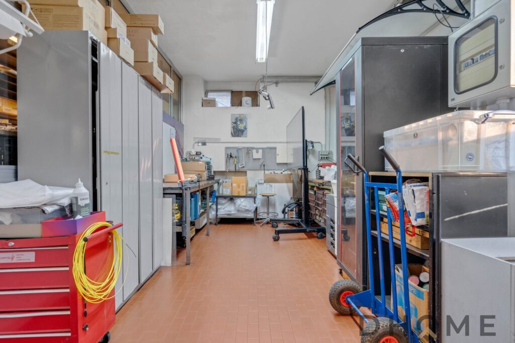 Ripostiglio industriale con scaffalature e attrezzature per la manutenzione di veicoli.