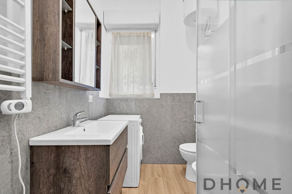 Lavanderia moderna con mobile in legno, lavabo e asciugatrice, spazio funzionale e luminoso.