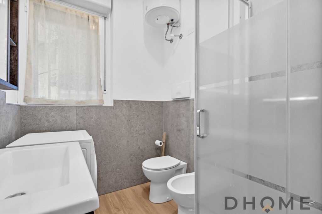 Lavatrice in bagno con pareti grigie e finestra bagno suddivisa, arredo moderno.