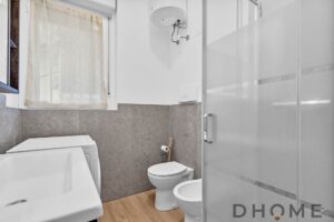 Lavatrice in bagno con pareti grigie e finestra bagno suddivisa, arredo moderno.