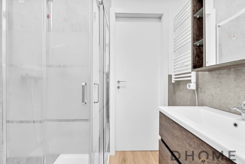 Specchio bagno moderno con lavabo in legno e radiatore scaldasalviette bianco.