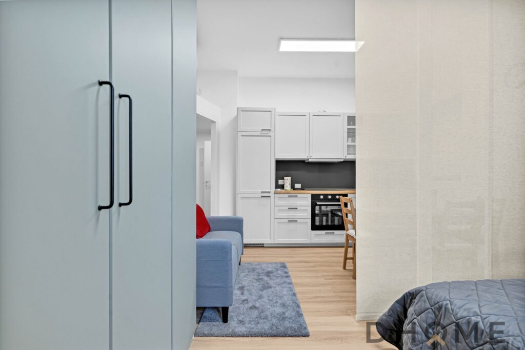 Armadio color salvia in soggiorno con cucina attrezzata a vista in stile moderno.