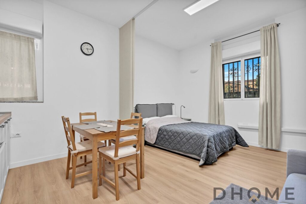 Camera da letto moderna con doppi letti e finestra panoramica, ambienti accoglienti e luminosi.