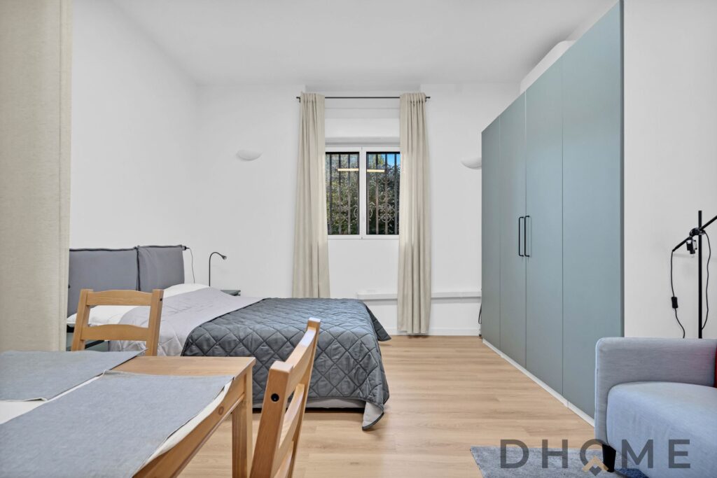 Letto matrimoniale in camera moderna, arredamento minimalista, finestre luminose, stile contemporaneo.