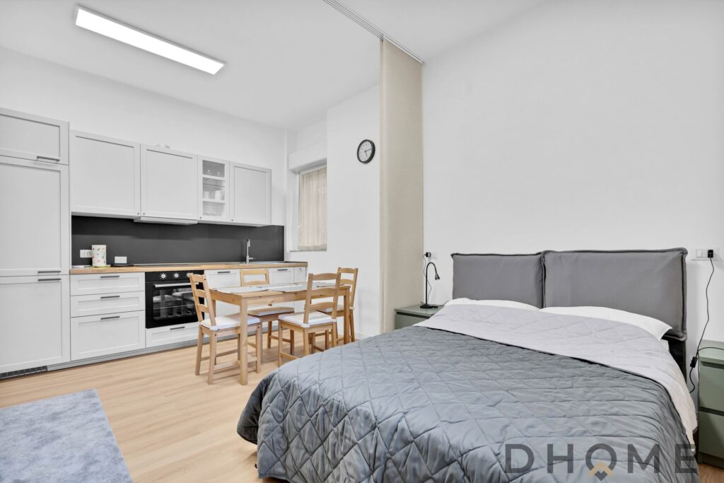 Soggiorno con cucina moderna e camera da letto in stile minimalista, arredamento funzionale e luminoso.