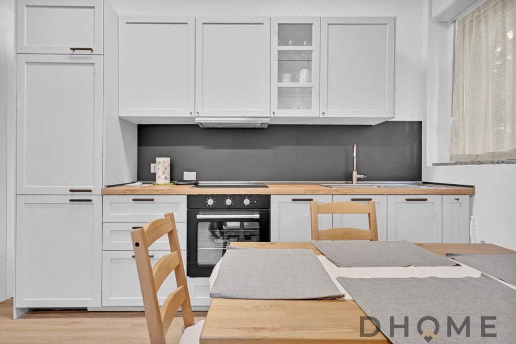 Cucina moderna con mobili bianchi e piano in legno, spazio funzionale e stile minimalista.