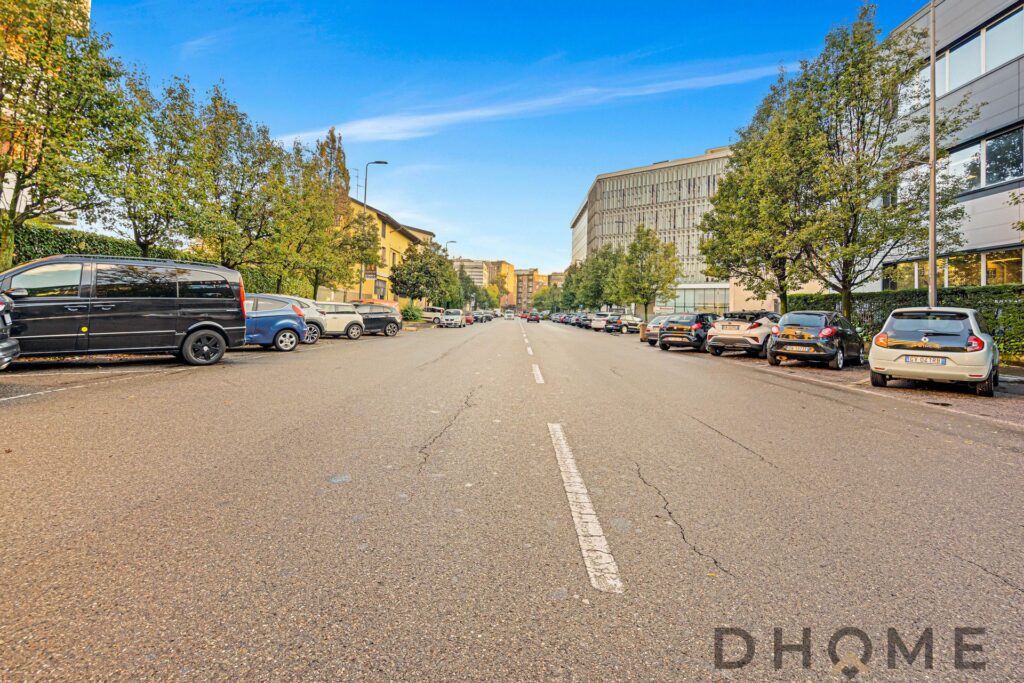 Area di parcheggio urbana con alberi e moderni edifici aziendali, spazio aperto e ben curato.