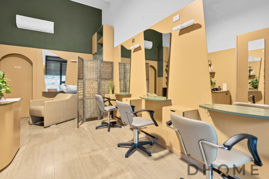 Salone di parrucchiere moderno con postazioni di lavoro e specchi.