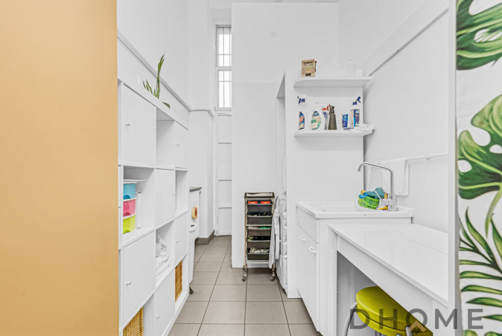Lavanderia domestica con piani di lavoro e scaffalature bianche per l'organizzazione domestica.