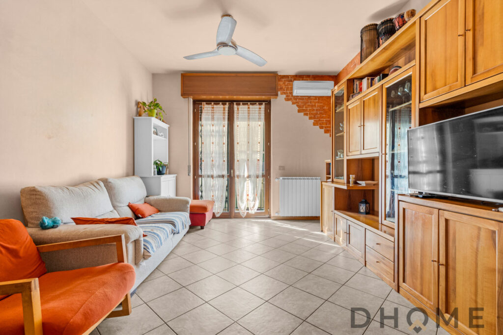 Soggiorno con mobile in legno, divano e TV, arredamento accogliente e luminoso verde ingresso in casa.