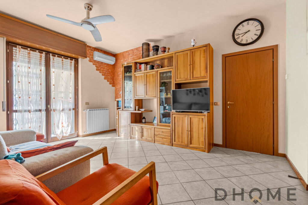 Finestra con tende in soggiorno con mobili in legno e TV.