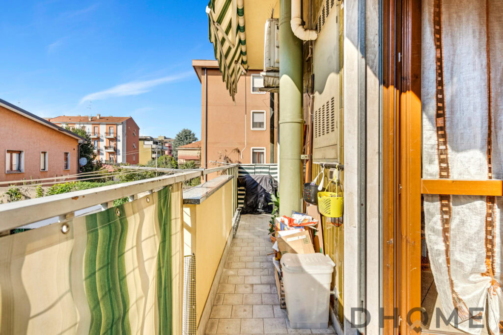 Balcone di un appartamento con arredi esterni e vista sui tetti cittadini.