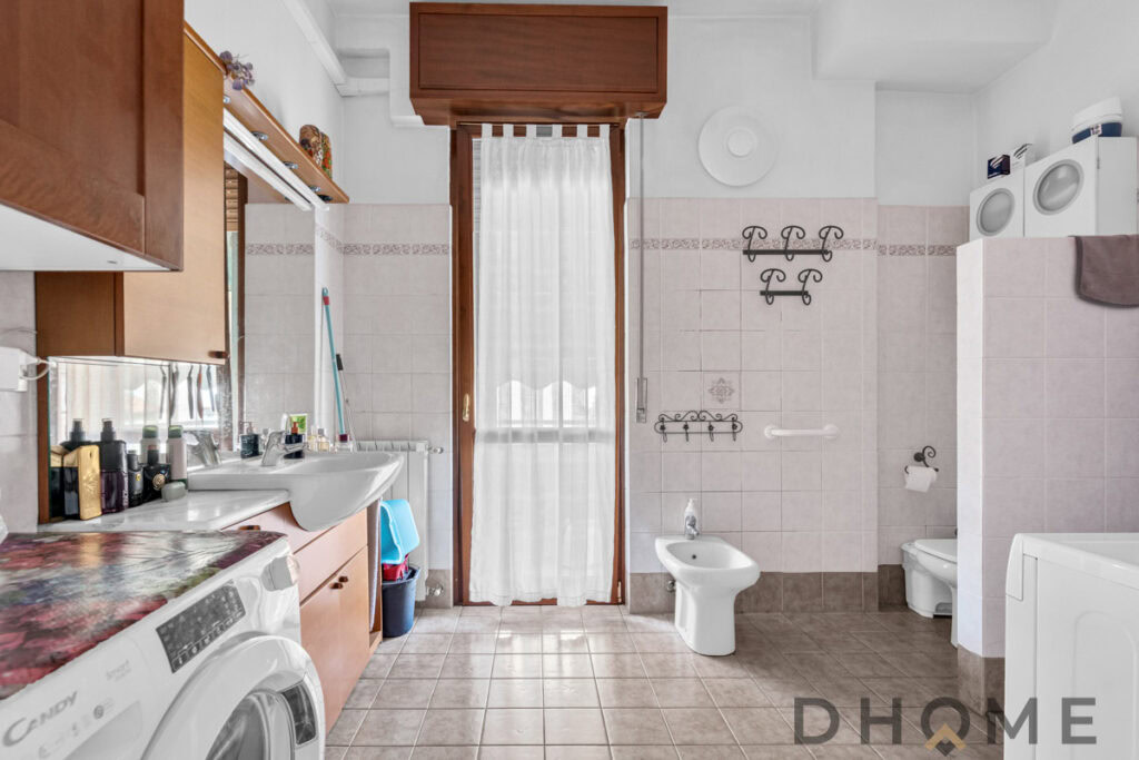 Lavanderia spaziosa con lavatrice, lavabo e zona lavaggio con arredi in legno e accessori pratici.