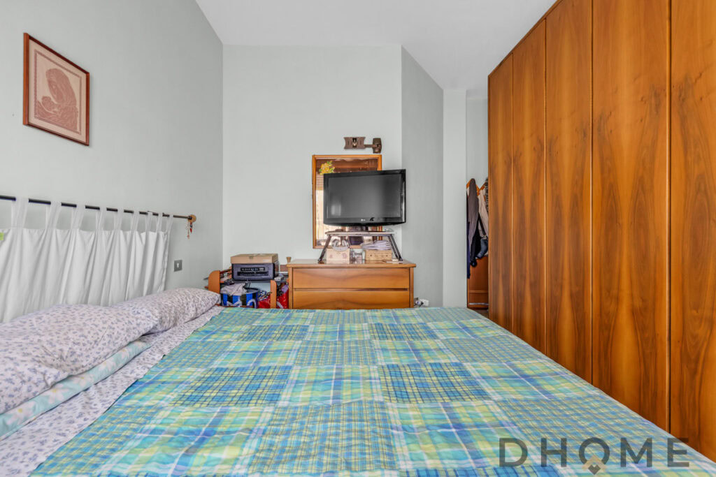 Letto matrimoniale con arredamento classico e armadio in legno massiccio, stanza da letto accogliente e funzionale.