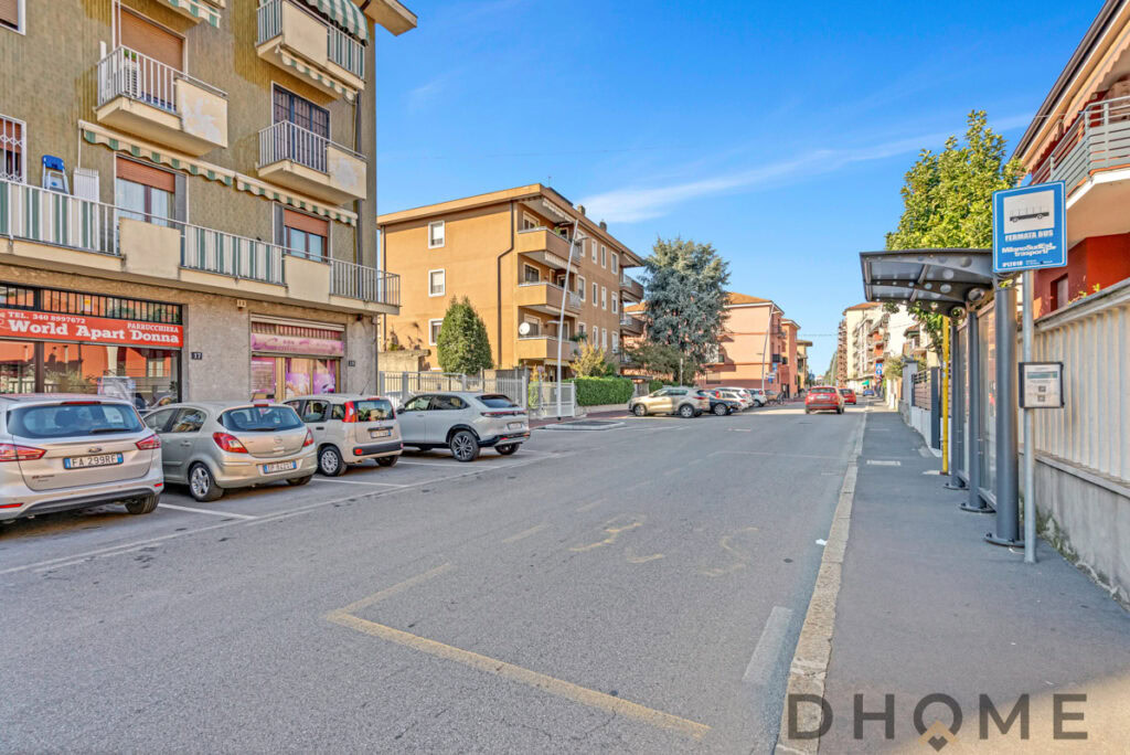 Parcheggio auto in zona urbana vicino a residence con negozi e fermata autobus, Italia.