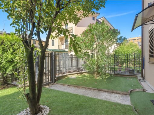 Verde giardino privato con piante e fiori, spazio esterno ben curato, casa con balcone e recinzione in ferro battuto.