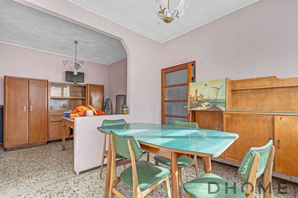 Soggiorno con tavolo e sedie, arredi in stile vintage, ambiente luminoso e accogliente.