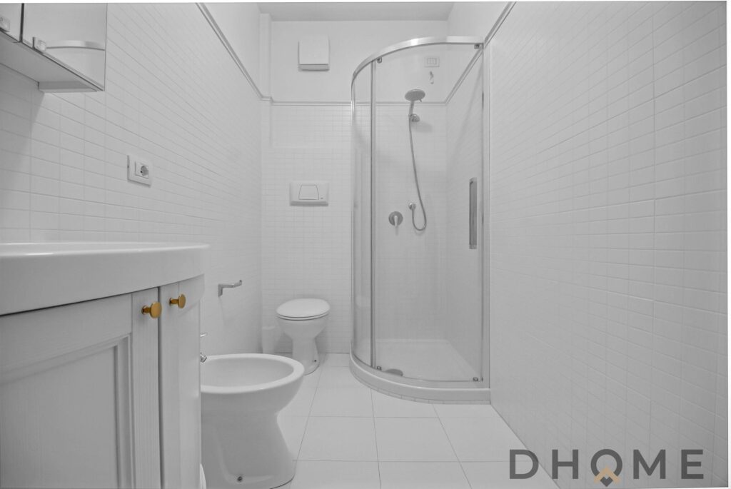 Bagno spazioso con box doccia curvo e sanitari eleganti.