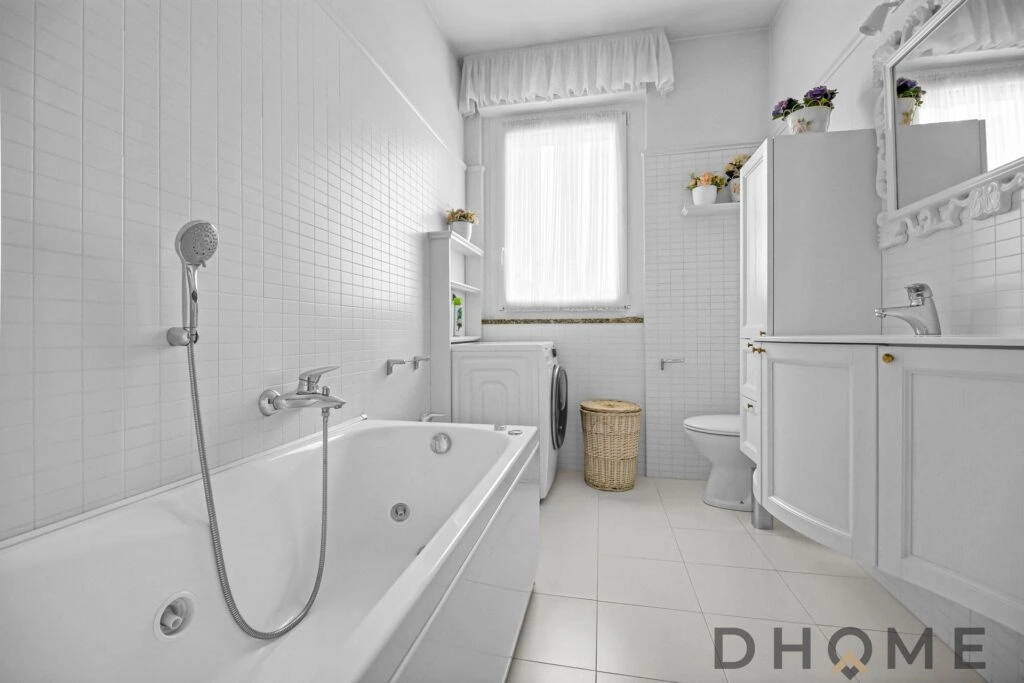 Bagno spazioso con vasca, finestra luminosa e arredi raffinati in stile minimalista.