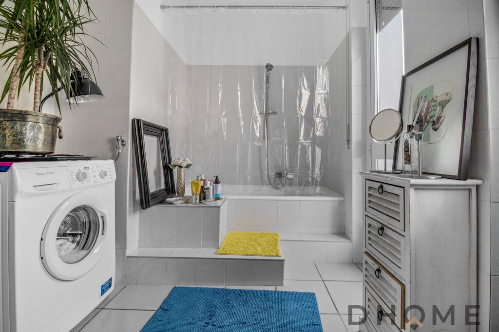 Bagno luminoso e moderno con vasca e lavatrice in zona strategica a Como.