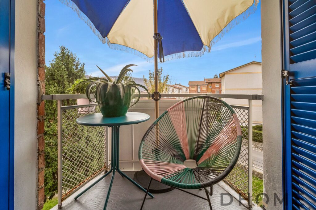 Balcone con sedie e ombrellone in zona strategica a Como, ideale per relax e vista sulla città.