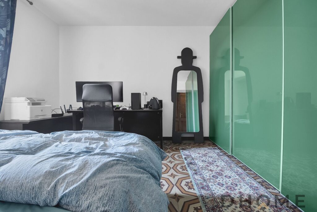 Camera da letto con armadio verde e scrivania, ambiente luminoso e moderno.
