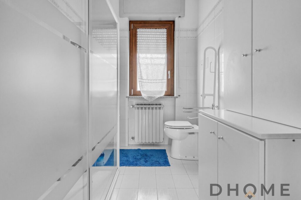 Bagno moderno e luminoso in villa singola a Madone, con arredi bianchi e finestra.