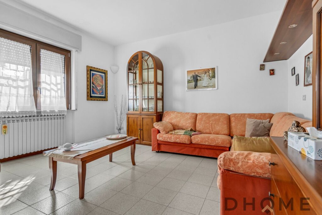 Villa in vendita a Madone, soggiorno luminoso con divano arancione e arredi funzionali.