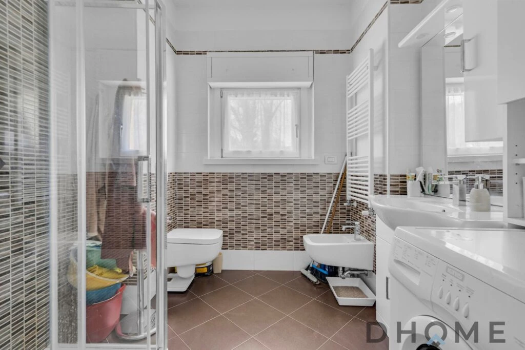 Bagno spazioso con sanitari, lavatrice e finestra naturale.