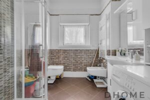 Bagno spazioso con sanitari, lavatrice e finestra naturale.