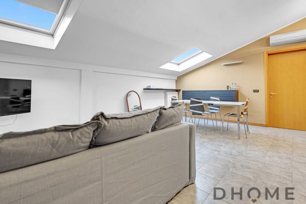 Soggiorno in mansarda con ampie finestre e luce naturale, ideale per un bilocale in affitto a Maciac.