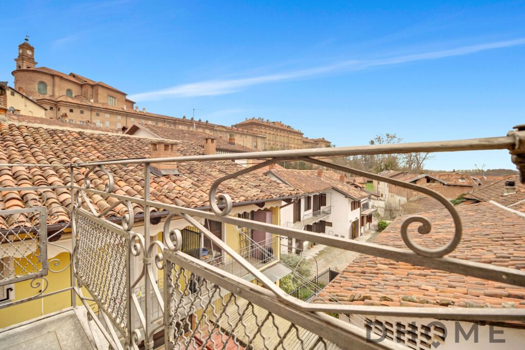 Balcone con ringhiera decorativa e tetti in terracotta.