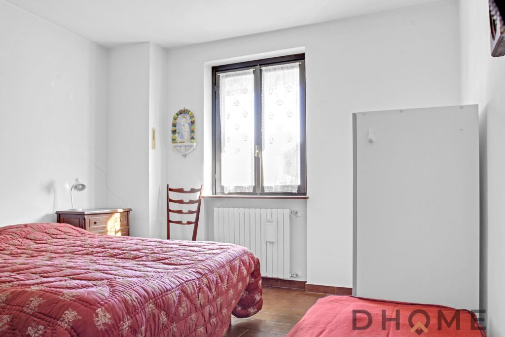 Camera matrimoniale con finestra e arredi semplici, ideale per soggiorno tranquillo.