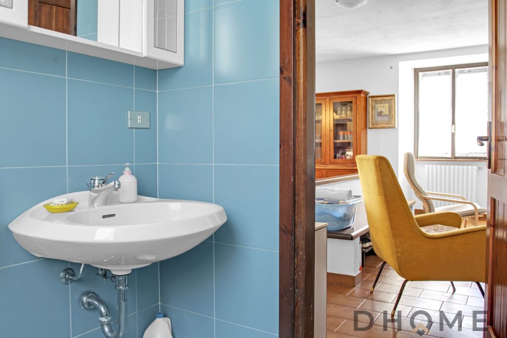 Bagno con lavabo e piastrelle azzurre in casa indipendente a Primaluna.