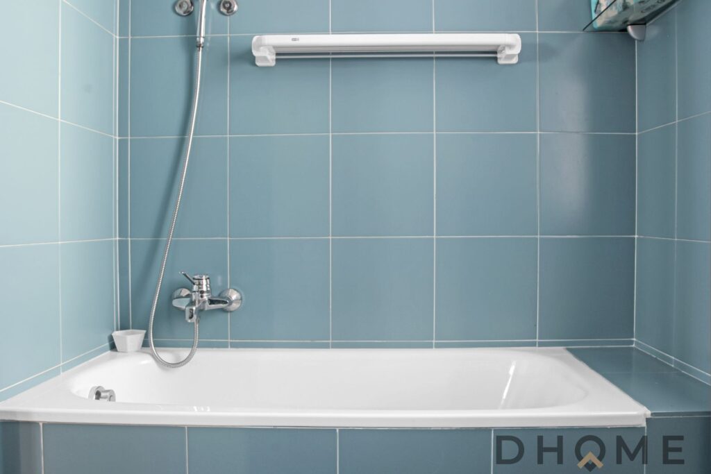 Bagno con piastrelle azzurre, vasca e doccia in un appartamento quadrilocale a Primaluna.