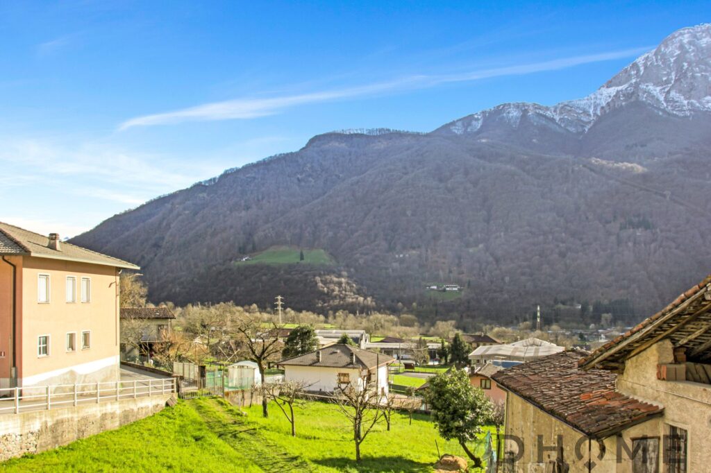 Immagine di un paesaggio naturale con montagne, case e vegetazione verde.