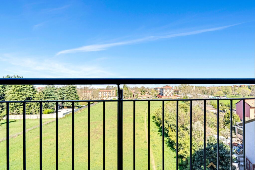 Balcone con vista su giardino e cielo azzurro, ideale per investimento e living luminoso.